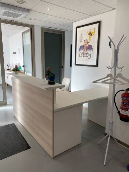 Empfangsbereich der Inselproktologie Mallorca mit freundlicher Atmosphäre. Im Hintergrund das Kunstwerk "Big Daddy" von Niki de Saint Phalle und ein Blick zur Kaffeebar im Wartezimmer.