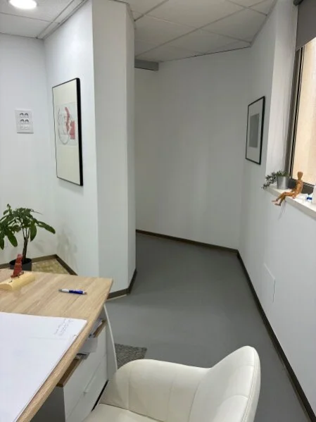 Durchgang vom Sprechzimmer zum proktologischen Behandlungsraum, mit Kunst an den Wänden, hell und freundlich gestaltet